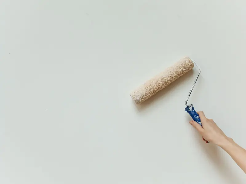 Ruka valjkom kreči zid u svijetloj boji